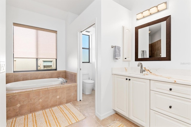 bathroom featuring a relaxing tiled tub, toilet, vanity, and tile patterned flooring