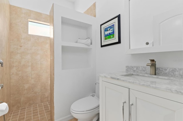 bathroom with toilet, a tile shower, and vanity