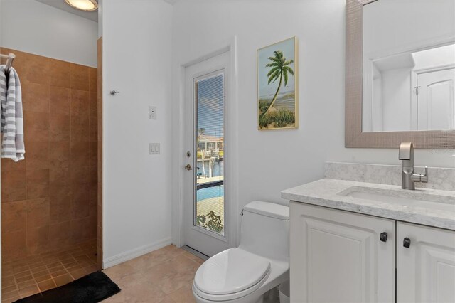 bathroom featuring tile patterned floors, toilet, vanity, and a tile shower