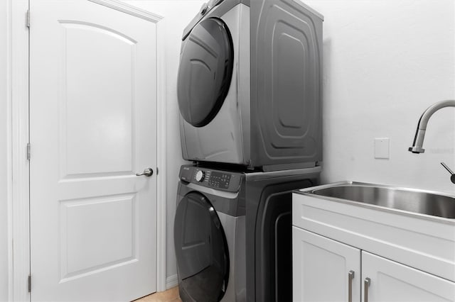 laundry area featuring cabinets, sink, and stacked washing maching and dryer