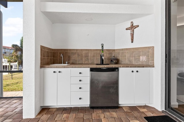 bar with tasteful backsplash, tile countertops, fridge, sink, and white cabinetry