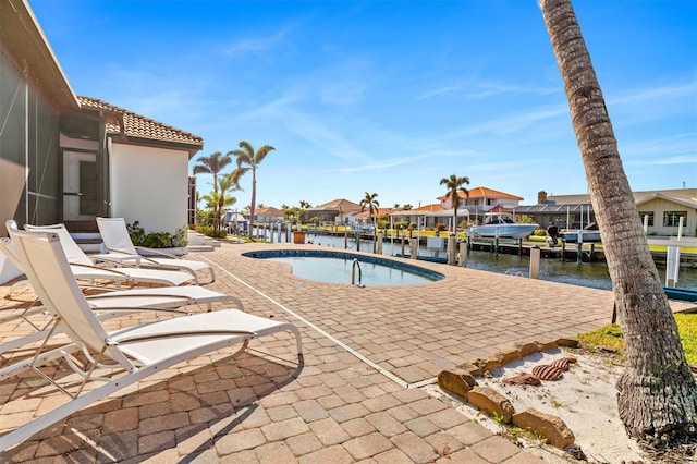 view of swimming pool with a patio area, a water view, and a boat dock