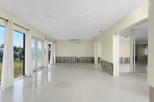 tiled empty room with a wall mounted AC and french doors