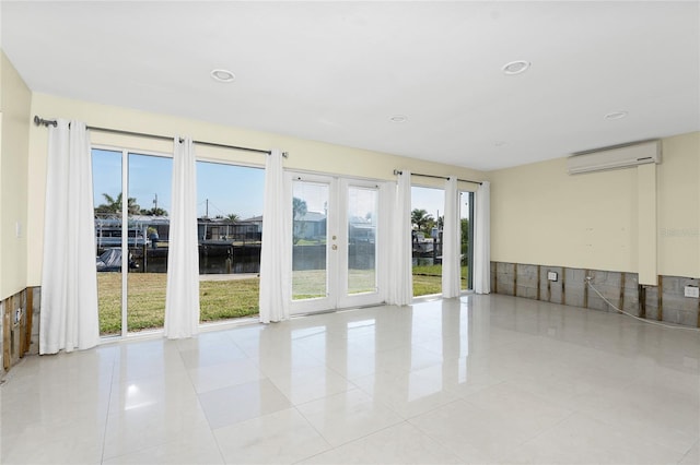 spare room with a water view, a wall mounted air conditioner, and light tile patterned floors