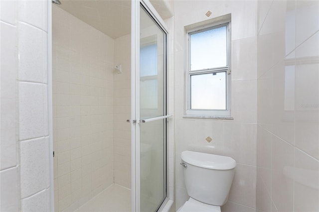 bathroom with toilet, a shower with shower door, and tile walls