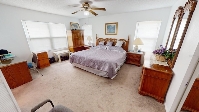 bedroom featuring a textured ceiling, light colored carpet, and ceiling fan