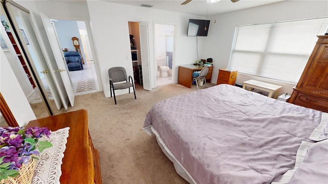 bedroom featuring connected bathroom, light colored carpet, and ceiling fan