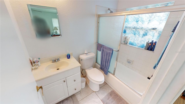 full bathroom featuring tile patterned flooring, bath / shower combo with glass door, vanity, and toilet