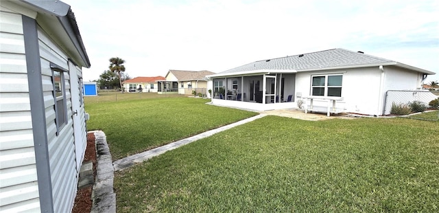 rear view of property featuring a sunroom and a yard