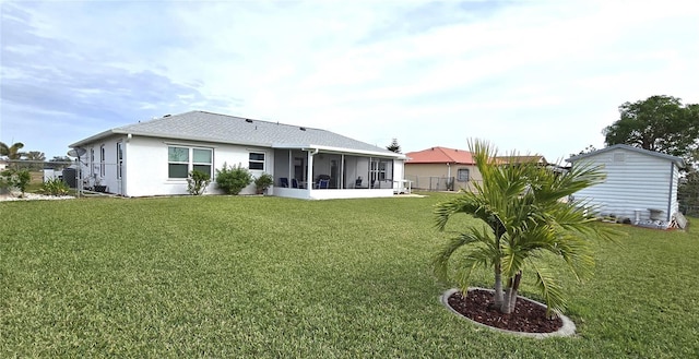 rear view of house with a sunroom and a lawn