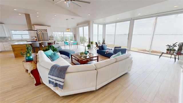 living room with ceiling fan, light hardwood / wood-style floors, and high vaulted ceiling