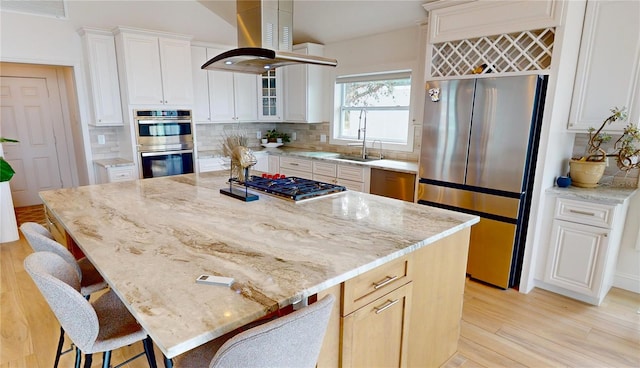 kitchen with island range hood, light stone counters, stainless steel appliances, and a kitchen island