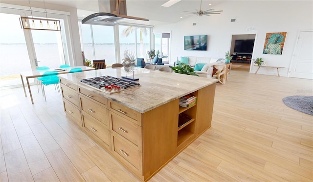 kitchen with ceiling fan, decorative light fixtures, light wood-type flooring, stainless steel gas cooktop, and light stone countertops