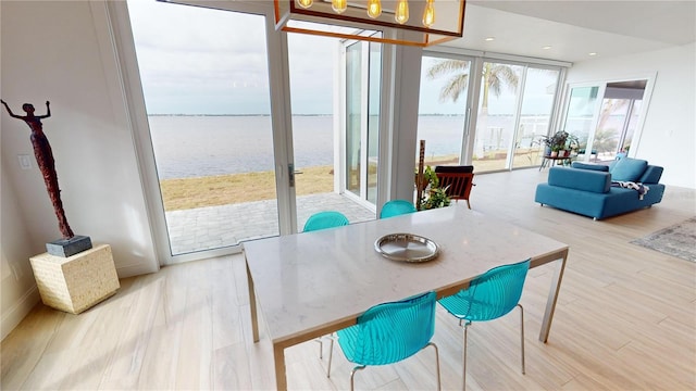 dining area with a water view, floor to ceiling windows, and light hardwood / wood-style flooring