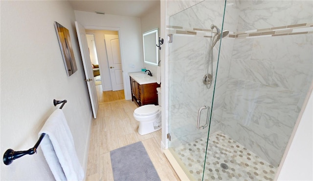 bathroom with vanity, toilet, wood-type flooring, and a shower with door