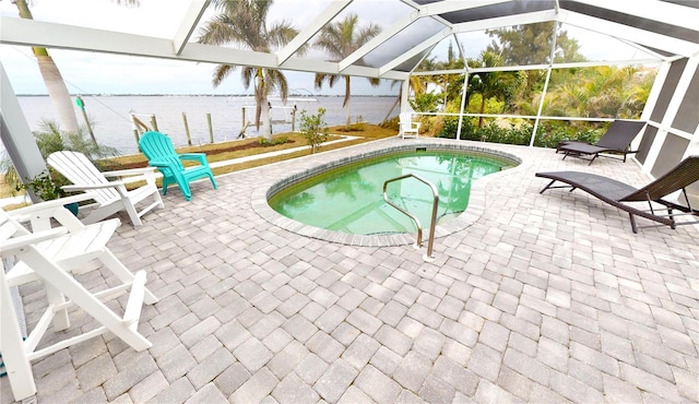 view of swimming pool featuring glass enclosure, a water view, and a patio