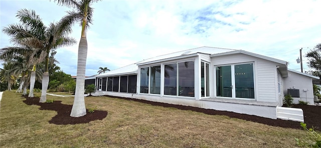 view of side of home featuring central AC, a sunroom, and a yard