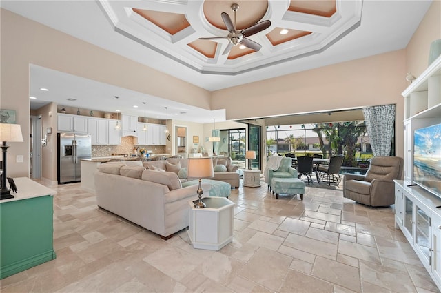 living room featuring coffered ceiling, a towering ceiling, ceiling fan, and crown molding