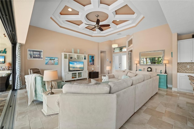 living room with beamed ceiling, ceiling fan, coffered ceiling, a high ceiling, and crown molding