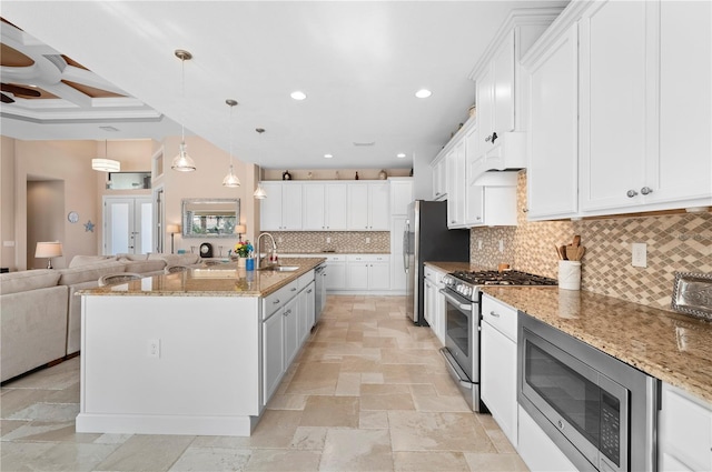 kitchen featuring stainless steel appliances, sink, decorative light fixtures, white cabinetry, and a center island with sink