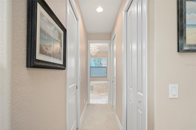 corridor with a notable chandelier and carpet flooring