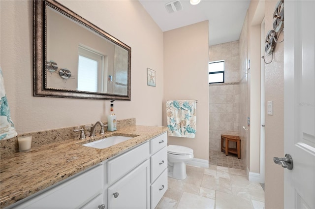 bathroom featuring vanity, walk in shower, and toilet