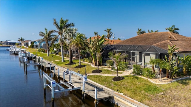 view of dock with a yard, glass enclosure, and a water view