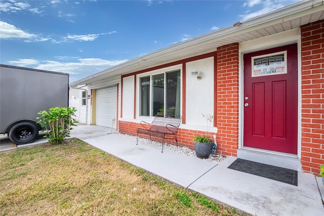 view of exterior entry with a yard and a garage