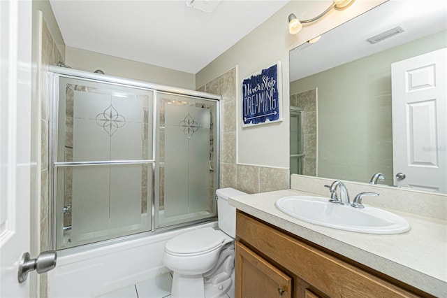 full bathroom featuring tile patterned floors, vanity, toilet, and combined bath / shower with glass door