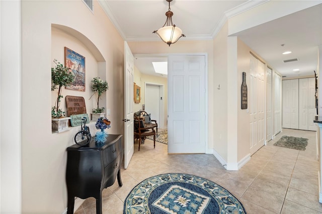 entryway with ornamental molding, visible vents, baseboards, and light tile patterned floors