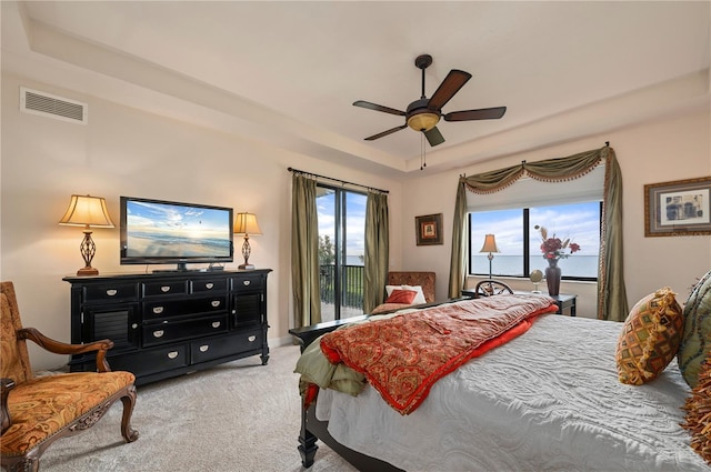 bedroom featuring access to exterior, a tray ceiling, light colored carpet, visible vents, and ceiling fan