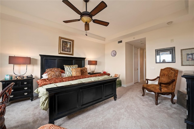 bedroom featuring a tray ceiling, light colored carpet, visible vents, ceiling fan, and baseboards