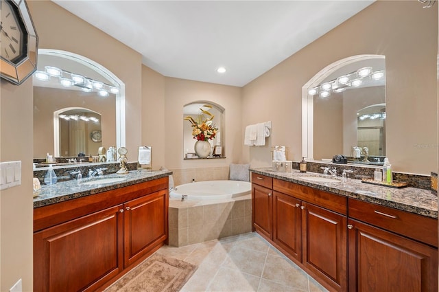 full bath featuring two vanities, a sink, a bath, and tile patterned floors