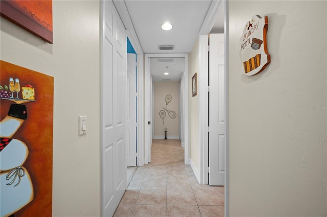 hallway featuring light tile patterned floors, baseboards, and visible vents