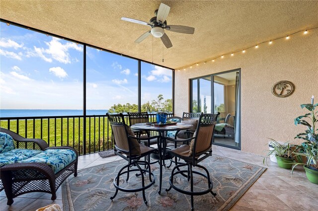 sunroom featuring a water view, a healthy amount of sunlight, and ceiling fan