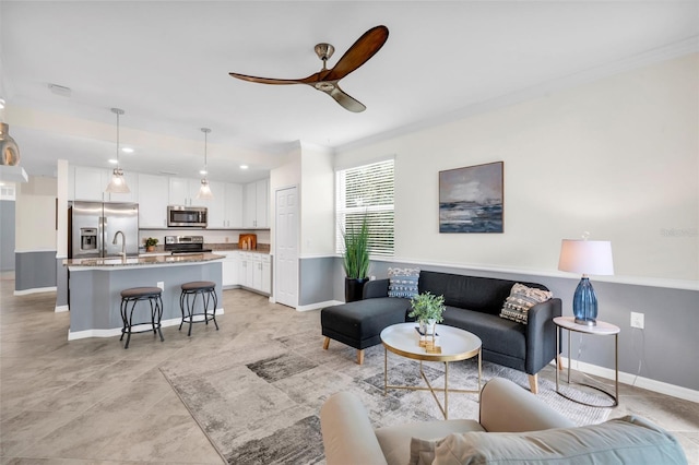 living room with ceiling fan, crown molding, and sink