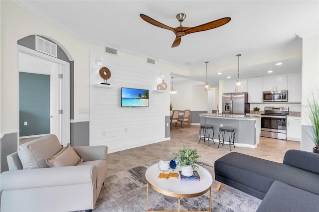 tiled living room featuring ceiling fan and ornamental molding