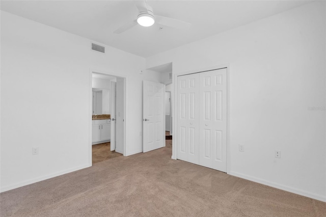 unfurnished bedroom with ensuite bathroom, light colored carpet, ceiling fan, and a closet