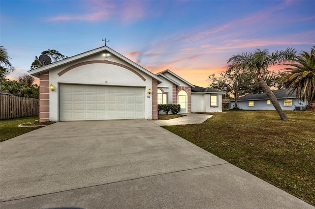 ranch-style home with a garage and a lawn