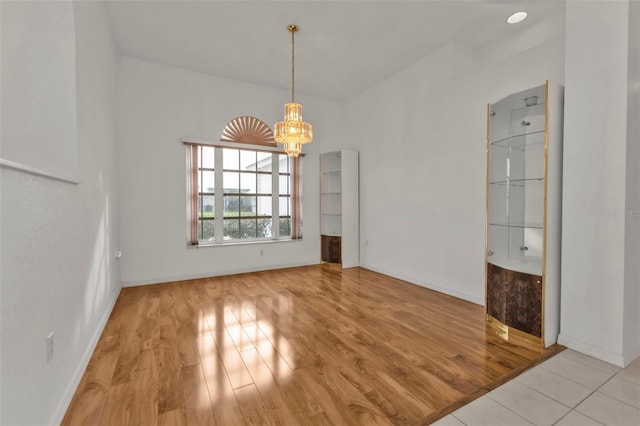 unfurnished dining area with a chandelier and light hardwood / wood-style floors