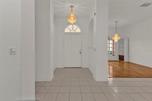 tiled foyer entrance featuring a notable chandelier