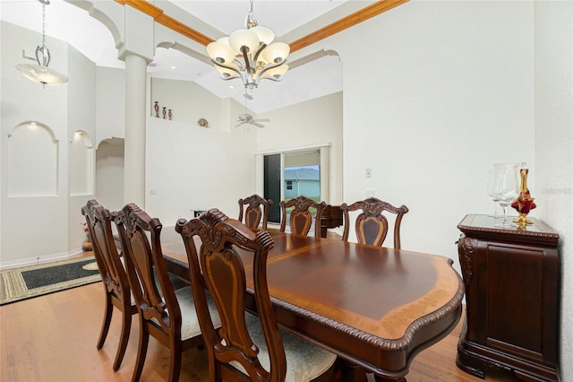 dining room featuring crown molding, vaulted ceiling, decorative columns, and light hardwood / wood-style flooring