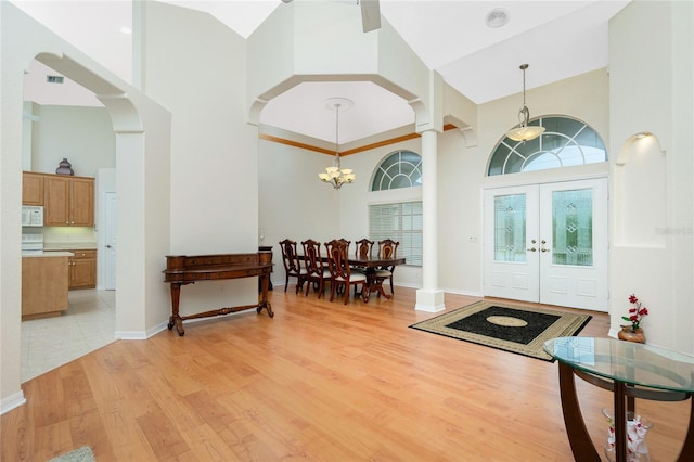 foyer entrance with an inviting chandelier, light hardwood / wood-style floors, french doors, and a high ceiling