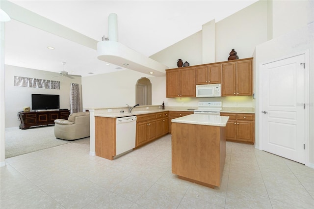 kitchen featuring sink, white appliances, a center island, kitchen peninsula, and ceiling fan