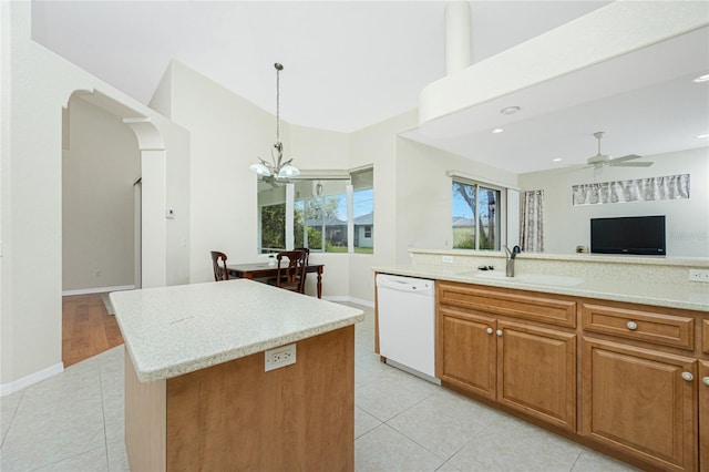 kitchen featuring light tile patterned flooring, sink, hanging light fixtures, white dishwasher, and a kitchen island