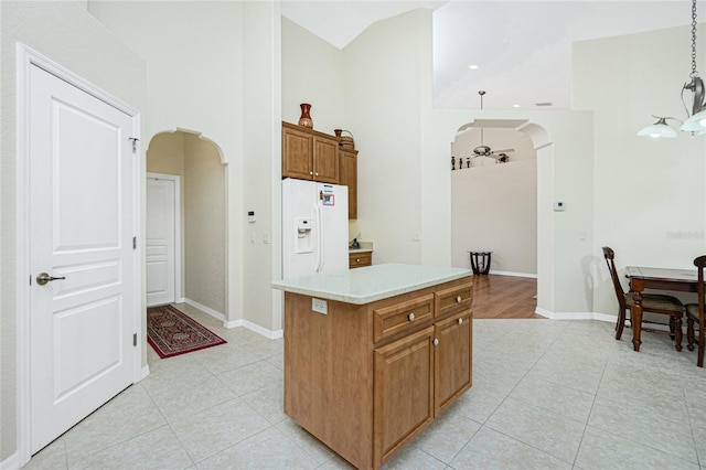 kitchen with a center island, high vaulted ceiling, hanging light fixtures, and white fridge with ice dispenser