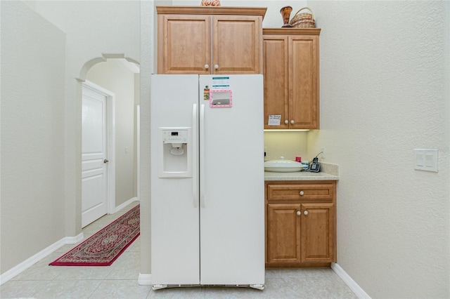 kitchen featuring white refrigerator with ice dispenser and light tile patterned flooring