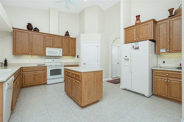 kitchen featuring sink, a high ceiling, a center island, ceiling fan, and white appliances