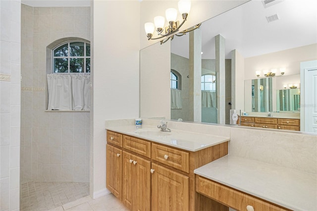 bathroom featuring a notable chandelier, vanity, tiled shower, and tile patterned floors