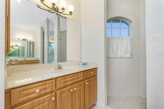 bathroom featuring vanity, a chandelier, and a tile shower